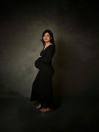 A full-length view of the simple black dress. This minimalist approach puts all the focus on the beautiful shape of the expecting mother.