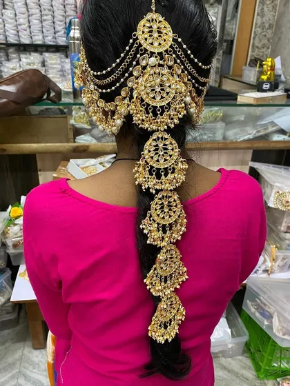 Complete your bridal hairstyle with this stunning gold-plated hair accessory, known as a braid paranda. This intricate piece is available for rent and adds a traditional, royal touch to your wedding look.