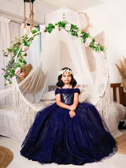 Every little girl deserves to feel like a princess. For this kids' photoshoot, she’s wearing a sparkling navy blue ball gown and sitting on our boho-themed hanging chair, creating a perfect fairytale moment.