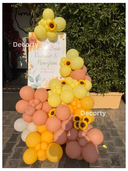 A welcome sign and balloon arrangement for the 'Parents to Bee' baby shower, decorated with sunflowers to match the cheerful theme.