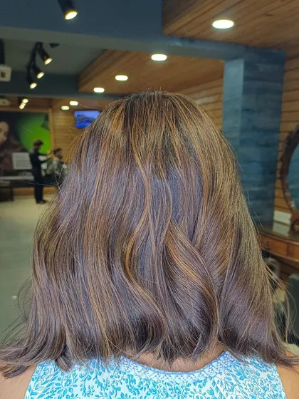 A seamless caramel highlight look on medium-length hair. The subtle color adds depth without being overpowering.
