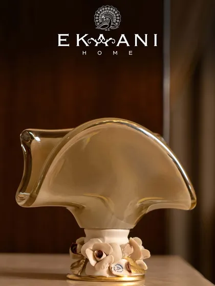 A sculptural vase from Murano, this piece blends a fluid, abstract form with delicate floral accents at the base. Handcrafted in glass and ceramic, it is a quiet showstopper, graceful and one of a kind.