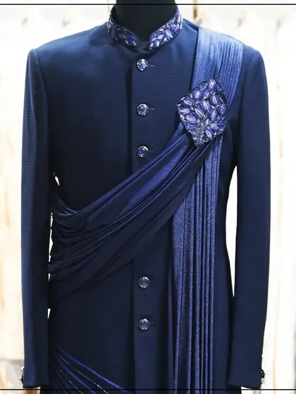 A navy blue Indo-Western outfit with a stylishly draped sash and a jeweled brooch. This design is a perfect blend of tailoring and draping.