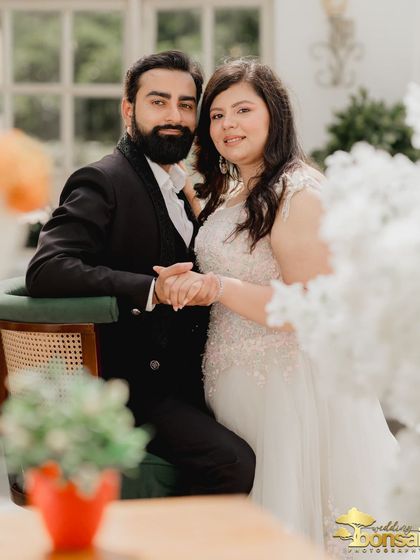 A close-up portrait that captures the couple's happy and relaxed expressions. The framing with the flowers adds a soft, romantic touch.