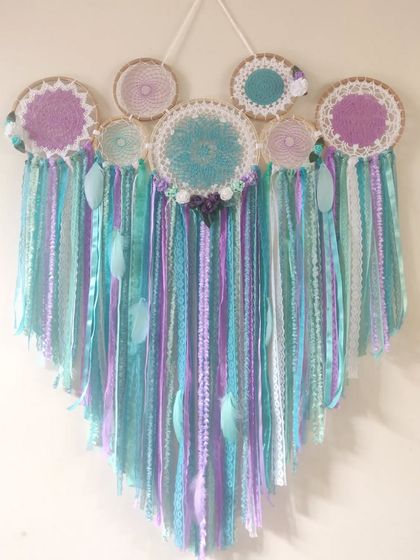 A mermaid-themed dreamcatcher for those who love the sea. The combination of turquoise, lavender, and white ribbons and lace creates a magical, underwater feel.