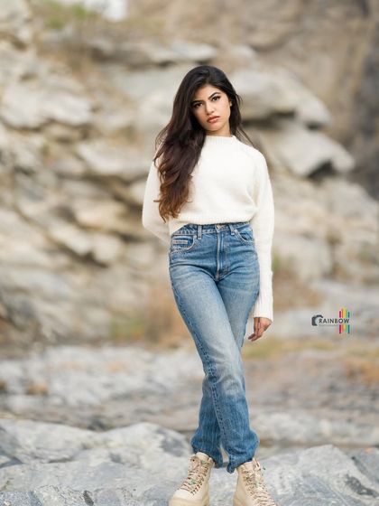 A full-length shot showcasing a complete winter outfit, including boots, against a textured rock background.
