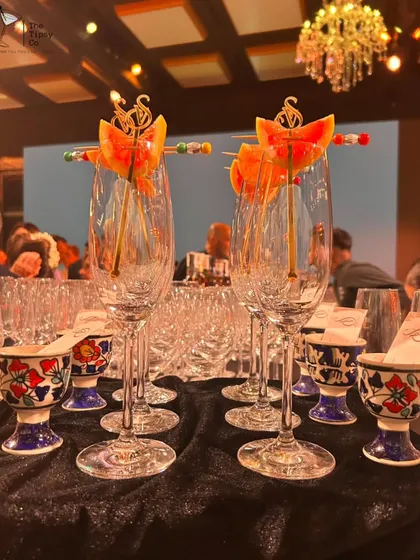 Elegance in every detail. Champagne flutes are pre-garnished with custom-branded skewers, ready for a toast, alongside unique ceramic shot glasses.