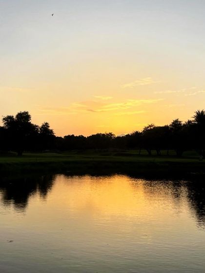 A serene sunset reflecting perfectly in a water hazard. These tranquil moments help build the patient and focused mindset required for golf.