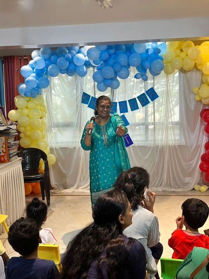 A storyteller captivates a room full of children with an animated performance during our Lit Fest, surrounded by festive balloon decorations.