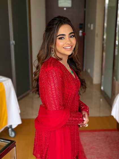 A beautiful Roka look in a vibrant red outfit. The makeup is soft and glowing, with a half-up hairstyle.