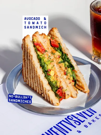 The Avocado & Tomato Sandwich is a fresh and vibrant option, served on grilled bread with a generous helping of smashed avocado and fresh tomatoes.