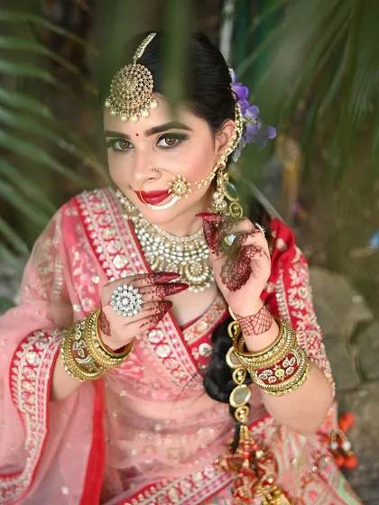 A beautiful close-up shot of a model in our red and pink lehenga, highlighting the detailed makeup and jewelry.