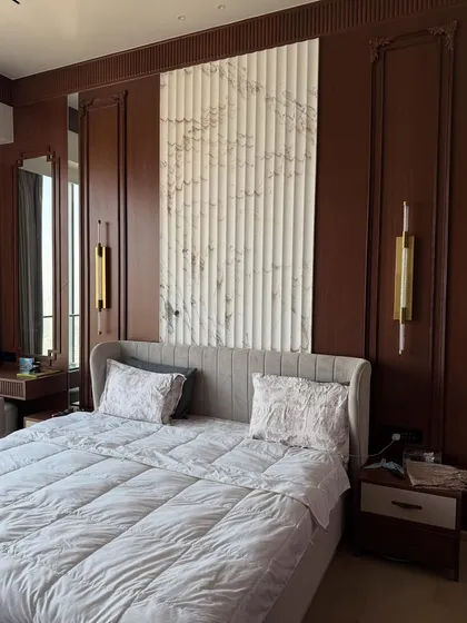The final look of the luxury master bedroom, featuring rich brown wood paneling, a fluted marble-finish headboard wall, and elegant bedside sconces.