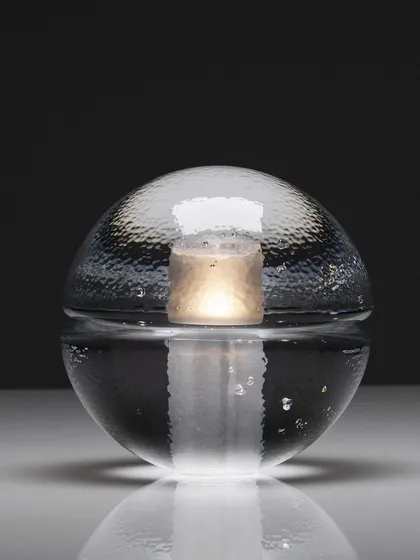 A studio shot of the clear glass 14p, its internal light source creating a beautiful, watery reflection on the surface below.