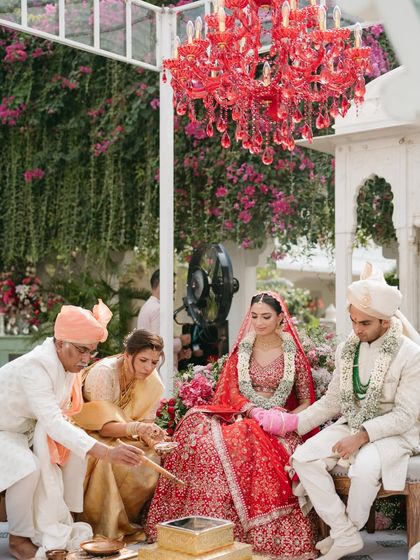 The wedding rituals are sacred. Here, the couple performs the ceremony under the custom-designed red chandelier, surrounded by family and an abundance of fresh flowers.