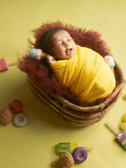 Even a little yawn is a moment worth capturing. This newborn, wrapped in a bright yellow swaddle, shows that babies are unpredictable, and sometimes the cutest moments are the most candid ones.