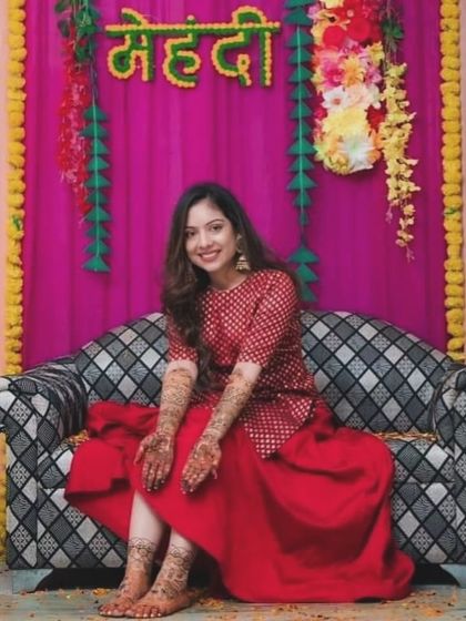 A happy client at her mehndi ceremony. Her hands and feet are adorned with beautiful, matching designs, making her look complete.