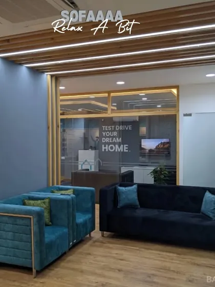 A comfortable lounge area within an office space, perfect for employees to relax or have a quick chat. The "Test Drive Your Dream Home" sign in the back is a nice touch.