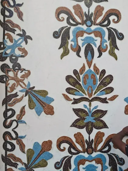 The mosaic panels being installed on the wall, revealing the intricate floral and damask-inspired patterns.
