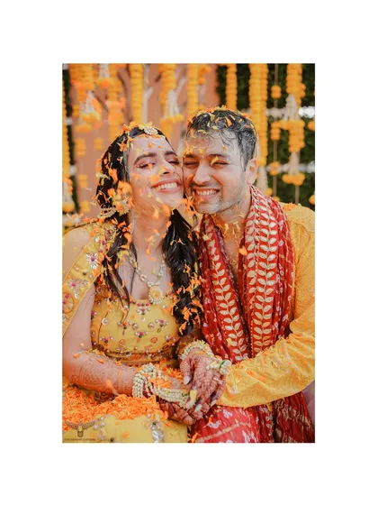 Drenched in love, laughter, and flower petals. This candid shot from a Haldi ceremony captures the couple in a moment of pure, uninhibited joy.
