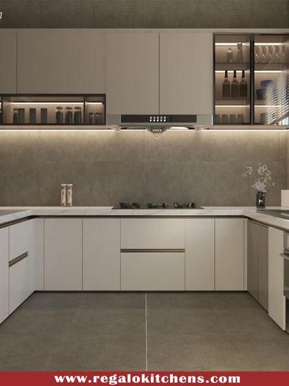 A U-shaped kitchen designed for maximum functionality. The layout provides extensive counter space and storage, with illuminated glass-front cabinets for displaying glassware. The concrete-grey finish adds a modern, industrial touch.
