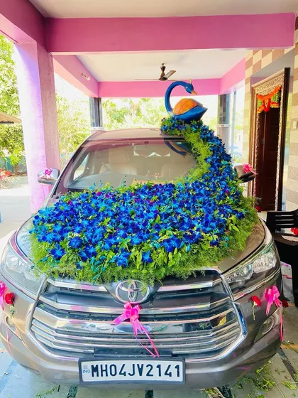 This is my signature peacock themed wedding car decoration on a Toyota Innova. The design features a beautiful peacock figure with a long, flowing tail of blue orchids and greenery covering the bonnet, making it a true showstopper.