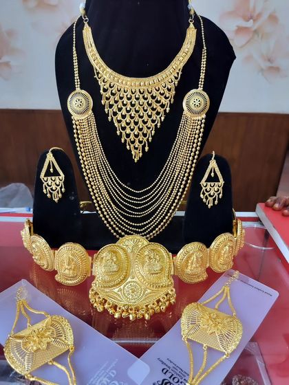 A traditional Bengali gold-look jewellery set, including a multi-layered necklace, armlets, and earrings.