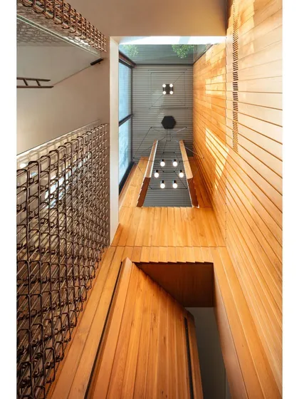 A worm's-eye view of the teak-clad double-height space, emphasizing its verticality and the careful integration of lighting fixtures to create a dramatic yet refined atmosphere.
