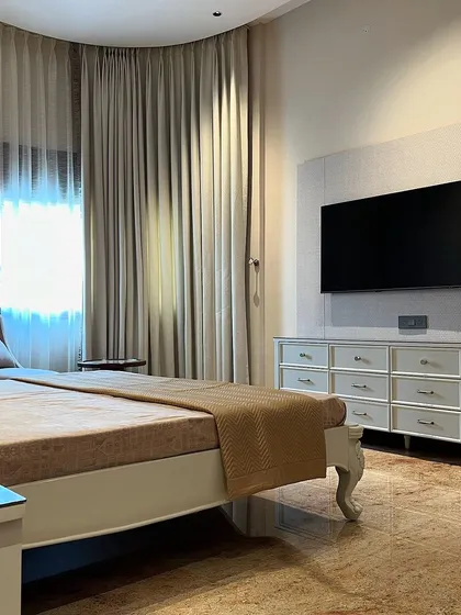 This view of the parent's room shows the custom-designed dresser and TV unit, which continues the classic theme with carved legs and elegant hardware. The design ensures the space is as functional as it is beautiful.