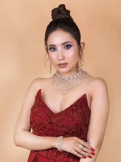 A stunning cocktail look in a red gown. The makeup is dramatic and glamorous, with cool-toned eyeshadow and a high-fashion feel, perfect for making a statement.