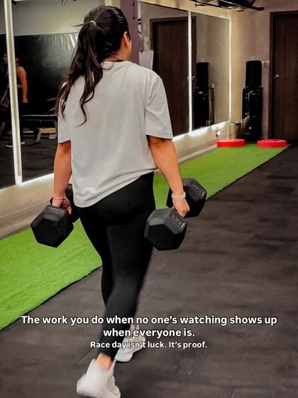 The work you do when no one is watching shows up on race day. A member performs farmer's walks with heavy dumbbells, a staple in our Hyrox program for building grip strength and core stability.