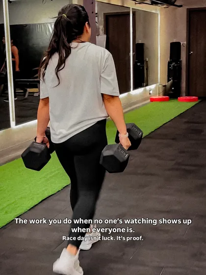 The work you do when no one is watching shows up on race day. A member performs farmer's walks with heavy dumbbells, a staple in our Hyrox program for building grip strength and core stability.