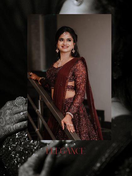 Elegance personified. A portrait of the bride in her shimmering maroon lehenga, with a focus on her henna-adorned hand and radiant smile.