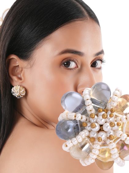 A model holding our Lumiere studs, crafted with grey and gold-toned beads for a calm and decorative expression.