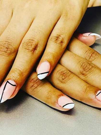 Abstract nail designs done beautifully. This set features a modern, geometric look with black lines over a white-tipped base.