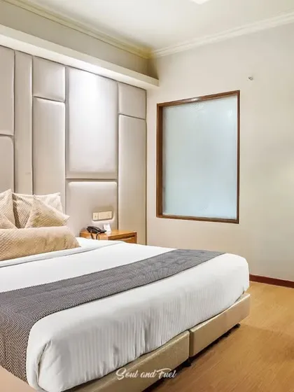The hotel room at night, with warm lighting creating a cozy and inviting ambiance. The padded headboard and clean lines of the furniture give the room a modern and luxurious feel.