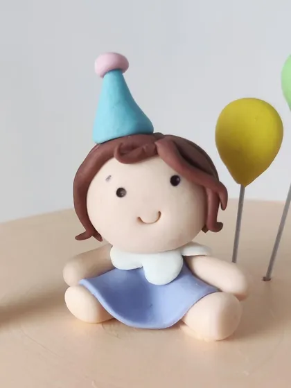A close-up of the sweet little girl figurine, handcrafted from fondant for a first birthday cake.