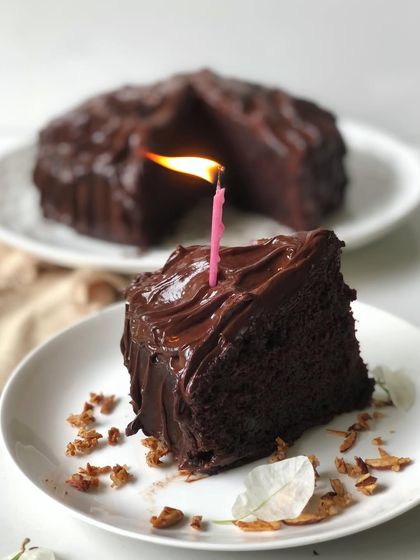 A classic birthday scene featuring a slice of my dense chocolate ganache cake with a single lit candle. It’s the perfect cake for any chocolate lover's celebration.