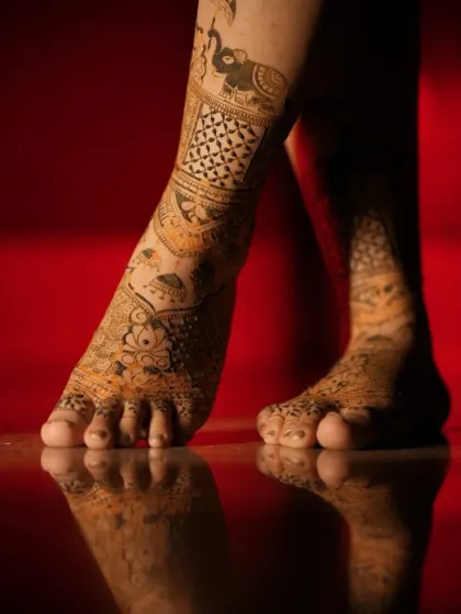An artistic shot of bridal feet with a rich henna stain, reflecting beautifully on the floor.