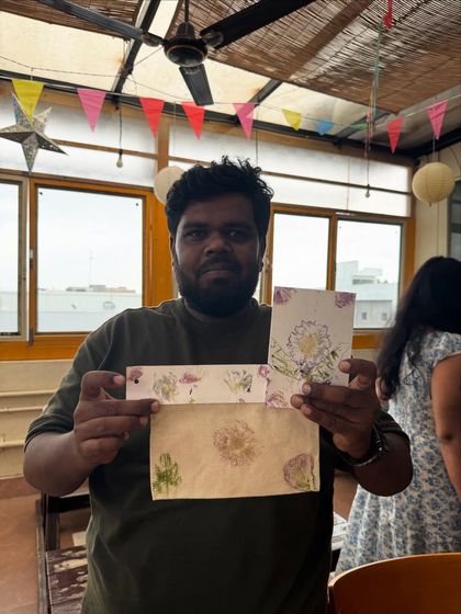 A participant showcasing his unique creations from the flower pounding workshop. He made a beautiful card and also decorated an envelope with natural floral prints.