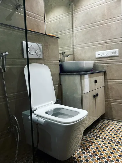 This bathroom design combines functionality with interesting textures. The floor features a vibrant geometric tile pattern, while the walls are clad in a more subdued, horizontally grooved tile. A floating vanity provides storage without crowding the floor space.