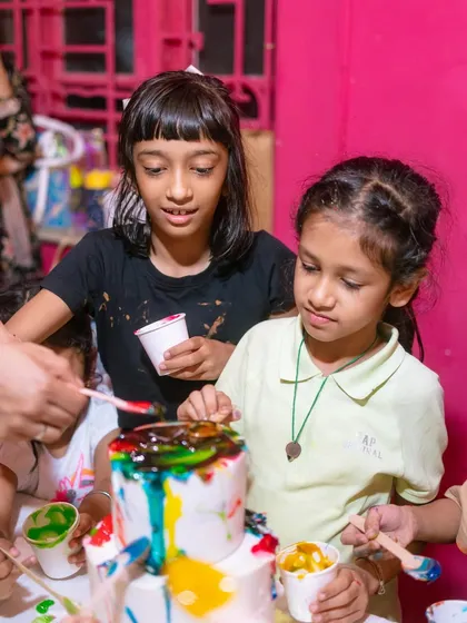 An interactive cake painting party for kids. Here, the children are having a blast adding edible paint to a blank white cake, turning it into their own colorful masterpiece.