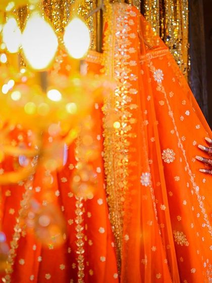 A unique angle peeking from behind the lehenga, with a chandelier creating beautiful foreground bokeh.