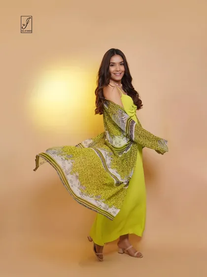 A bright and cheerful studio shot for a clothing brand, featuring a model in a lime green dress with a flowing printed shrug.