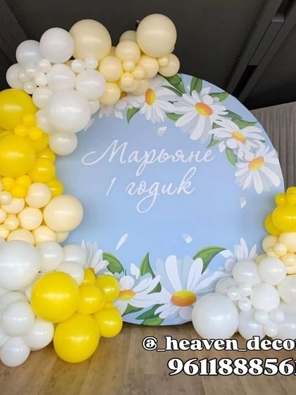 A cheerful and fresh daisy-themed setup. The decor features a circular backdrop with a daisy print, framed by a yellow and white organic balloon garland.