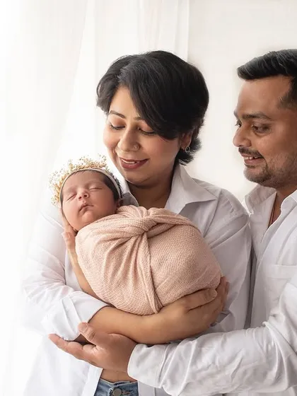 A bright and happy first family photo. The coordinated white shirts and the baby's adorable sleepy face make this a perfect newborn portrait.