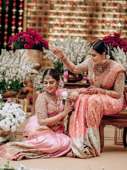 A playful moment between sisters, highlighting the beautiful floral decor and their elegant, coordinated sarees.
