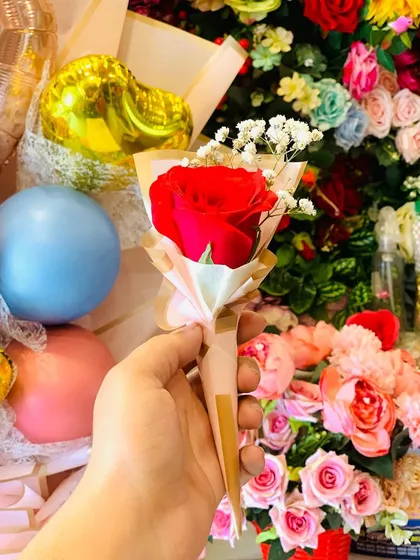 A single red rose cone bouquet, perfect for a simple and sweet gesture. The background shows my shop filled with colorful balloons and flowers.