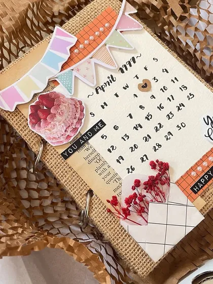 Another look at this anniversary scrapbook. The cover features a hand-drawn calendar marking the special date, along with cute banners and dried flowers. The burlap cover gives it a lovely rustic vibe.