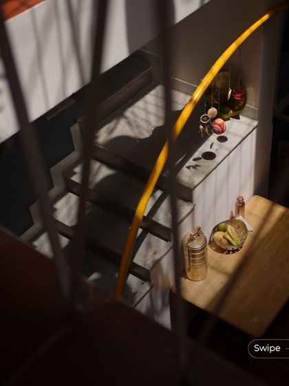 An overhead view of a small table and staircase landing, beautifully illuminated by dramatic shadows from a nearby window.